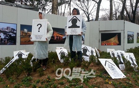 6일 오후, 최일배 코오롱 정리해고 분쇄투쟁위원장(좌)과 고동민 쌍용차지부 대회협력실장(우)이 화단으로 들어가 숨진 해고자와 그 가족을 추모하는 의미로 화단 안에 영정 그림을 세우고, 현수막을 걸었다. ⓒ 'go발뉴스'