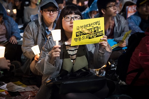13차 범국민촛불집회에 참여한 한 여학생이 한손에 촛불을 다른 한손에는 ‘국정원대선개입 박근혜대통령이 행동으로 책임져라!'라고 적힌 종이피켓을 들고 있다. ⓒ 이동호