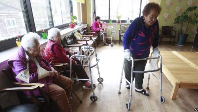 FILE – Kim Gun-ja, 89, right, former comfort woman who was forced to serve for the Japanese troops as a sexual slave during World War II, passes by other comfort woman Yi Ok-seon, 88, left, and Kim Wei-han, 86, at the House of Sharing, a nursing home.2차 세계대전 동안 일본군에 의해 성노예를 강요받은 전 ‘위안부’인 김군자(89세, 사진 오른쪽)씨가 ‘위안부’ 피해자 쉼터인 ‘나눔의 집’에서 다른 ‘위안부’인 이옥선(88세, 사진 왼쪽)씨와 김외한(86세)씨를 지나가고 있다.