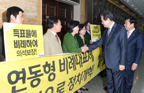 새누리당 김무성 대표와 원유철 원내대표가 2015년 12월12일 오전 서울 여의도 국회에서 열린 선거구 획정을 위한 여야 협상장으로 향하며 '연동형 비례대표제 도입 촉구 및 비례대표제 축소 반대' 등의 당 의견을 전달을 위해 피켓 시위중인 정의당 심상정 대표와 악수하고 있다. <사진제공=뉴시스>