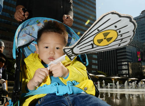 환경운동연합 회원들이 '일본산 수산물과 폐기물 수입 금지 촉구' 기자회견을 하는 가운데 유모차를 탄 아이가 방사능 표시가 붙은 조개 팻말을 들고 있다. <사진제공=뉴시스>