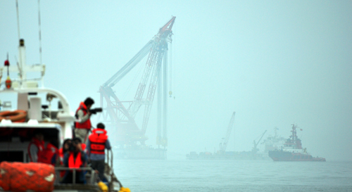 12일 오전 전남 진도군 동거차도 인근 세월호 침몰 사고 해역, 세월호 인양작업단 상하이샐비지호가 '선수 들기 공정'을 하고 있는 가운데 실종자·희생자 가족과 특별조사위원회 등이 현장 조사를 위해 접근하고 있다. <사진제공=뉴시스>