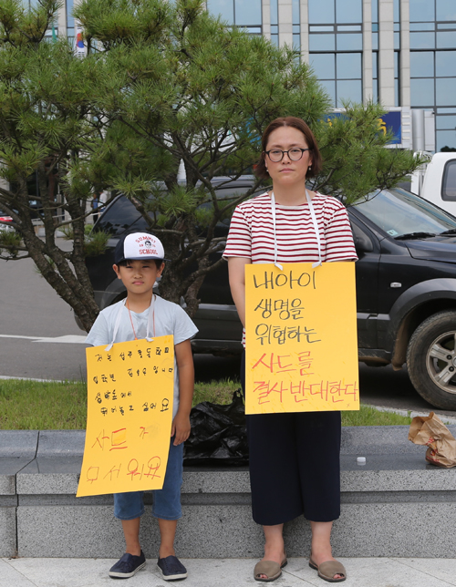 주한미군의 사드(THAAD·고고도미사일방어체계) 배치 지역이 지난 13일 경북 성주군 성산읍 성산포대로 최종 결정나자 시민단체와 성주 주민들이 강하게 반발하고 있다. 14일 오전 성주군청 앞에서 한 주민이 어린아이와 함께 '내 아이 생명을 위협하는 사드를 결사 반대한다'는 피켓을 목에 걸고 시위를 하고 있다. <사진제공=뉴시스>