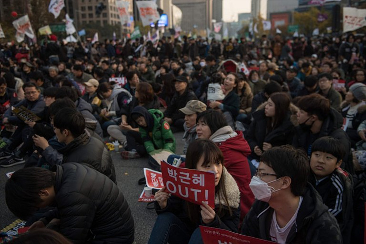 Anti-government protesters hold placards as they sit on a street in central Seoul (Picture: AFP/Getty Images)반정부 시위자들이 서울 도심의 거리에 앉아 사인을 들고 있다.