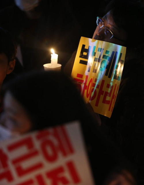 A protester holds up a candle during a rally in the city of Jeju (Picture: EPA/STRINGER SOUTH KOREA OUT)제주시 집회 중 한 시위자가 촛불을 들고 있다.