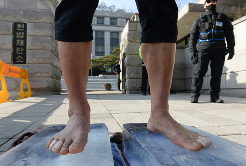 시민 조승환 씨가 4일 오후 서울 종로구 헌법재판소 정문 앞에서 맨발로 얼음 위에 올라 박근혜 대통령 퇴진 및 조기 탄핵 촉구하는 1인 시위를 하고 있다. <사진제공=뉴시스>