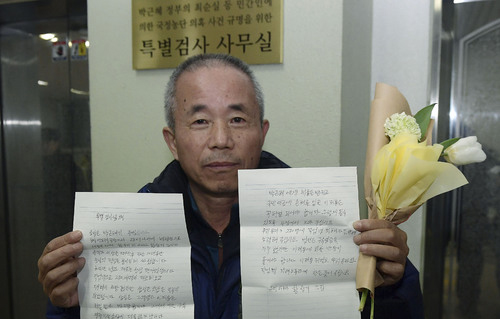 삼성반도체 입사 후 백혈병 진단을 받고 사망한 고 황유미 씨 아버지 황상기 씨가 19일 서울 대치동 특검사무실 앞에서 삼성그룹 이재용 부회장 처벌을 촉구하는 편지와 특검 수사를 응원하는 꽃을 들어보이고 있다. <사진제공=뉴시스>