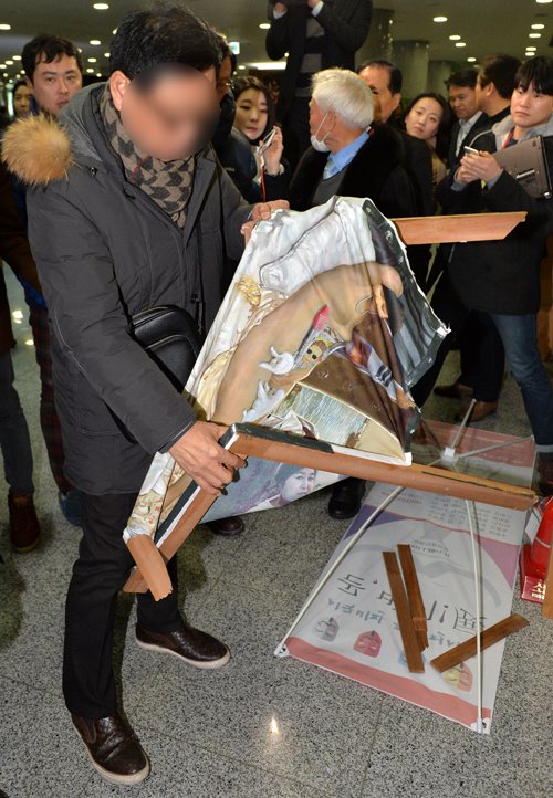 24일 오후 서울 여의도 국회 의원회관 1층 로비에서 한 박근혜 대통령 지지자가 훼손된 이구영 작가의 '더러운 잠'을 들어보고 있다. 더불어민주당 표창원 의원이 주최한 ‘곧, 바이! 展’에 걸린 이 그림은 박 대통령이 누드로 침대에 누워있는 모습을 묘사해 논란을 빚었다. <사진제공=뉴시스>