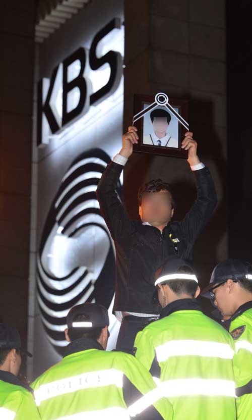 ▲ 세월호 희생자 유가족들이 2014년 5월8일 저녁 서울 여의도 KBS에서 보도국 간부가 밖으로 나올 것을 촉구한 가운데 한 유가족이 희생자 학생 영정을 들고 있다. <사진제공=뉴시스>