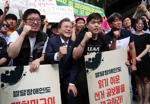 ▲ 문재인 대통령이 8일 오전 서울 종로구 청와대 인근 한 투표소에서 6·13 지방선거 및 국회의원 재보궐선거 사전투표를 마치고 장애인의 평등한 참정권을 요구하는 장애인단체 회원들과 사진촬영을 하고 있다. <사진제공=뉴시스>