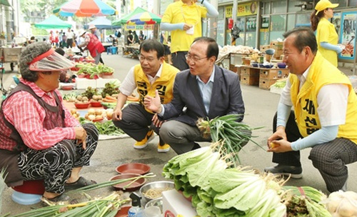 ▲ 고 노회찬 정의당 의원이 지난 6월4일 충주시의원 선거 사선거구에 출마한 채선병 후보 지원 유세 후 채소를 팔러 나온 상인을 만나 대화를 나누고 있는 모습. <사진제공=뉴시스>