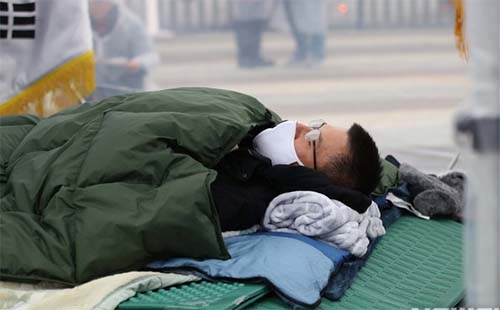 ▲ 황교안 자유한국당 대표가 단식중인 24일 오후 서울 청와대 분수대 앞 광장에서 열린 자유한국당 비상 의원총회에서 국민의례를 마치고 누워 있다. <사진제공=뉴시스>