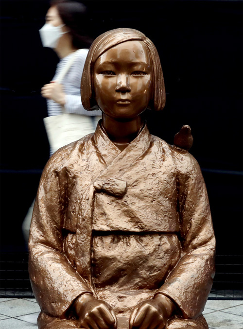 ▲ 일본군'위안부' 피해자 기림의 날인 지난 8월 14일 오전 서울 종로구 옛 일본대사관 앞 평화의 소녀상 뒤로 한 여성이 발걸음을 옮기고 있다. <사진제공=뉴시스>