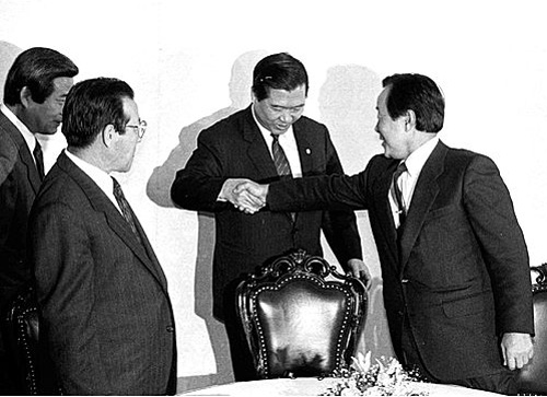 ▲ 1989년 12월13일 서울 여의도 국회 귀빈식당에서 김영삼, 김대중, 김종필 야 3당 총재 회담에 앞서 김대중 총재가 김영삼 총재와 악수하며 손을 잡아당겨 가운데 자리를 권하고 있는 모습. <사진제공=뉴시스>